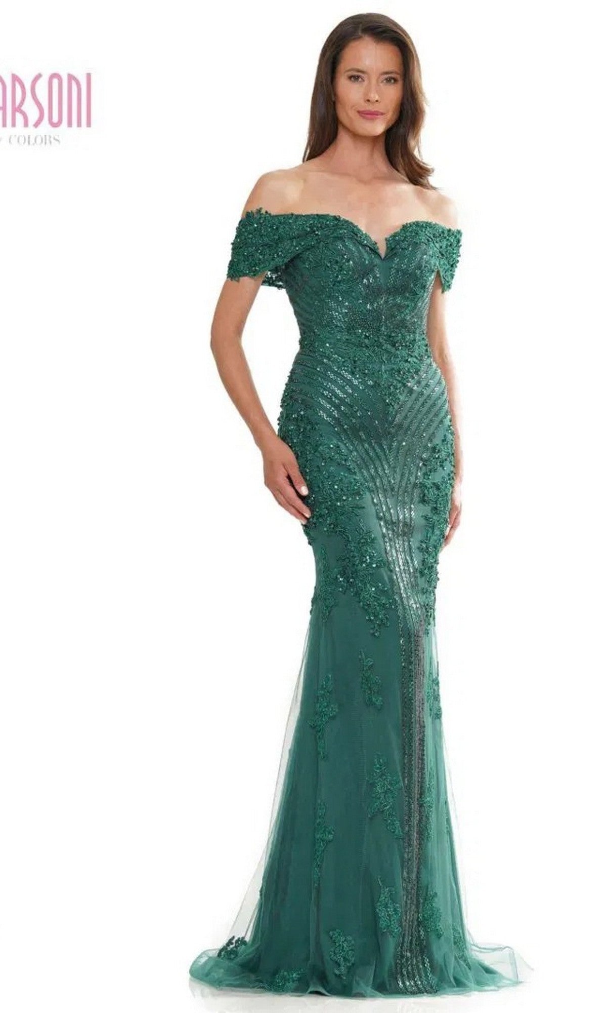 A woman poses in the Marsoni MV1275 long formal dress, shown in emerald with sequin and lace embellishments and an off-the-shoulder neckline.